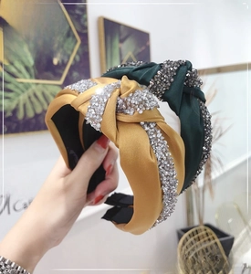 Detailed view of the sparkling crystal knotted headbands in ginger and dark green satin