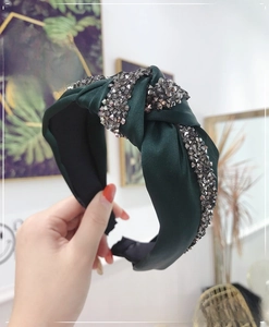 Detailed view of a dark green knotted headband featuring sparkling grey rhinestones