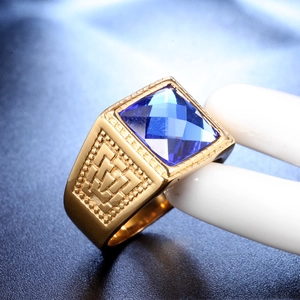 Close-up of golden signet ring with square blue gemstone and geometric side patterns