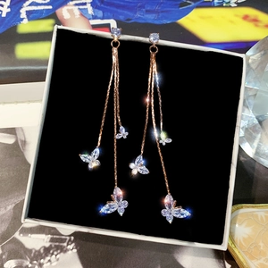 Detailed view of butterfly tassel earrings in rose gold on a black jewelry display box