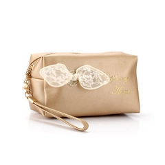 Detail of golden satin makeup bag with lace bow and Happy Home gold embroidery
