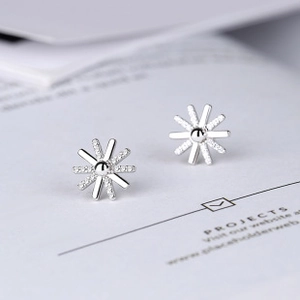Macro shot of silver sunburst stud earrings featuring delicate cubic zirconia insets