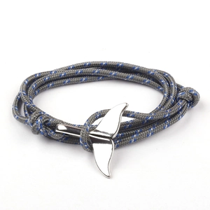 Gray and blue braided paracord bracelet with a polished silver whale tail anchor clasp