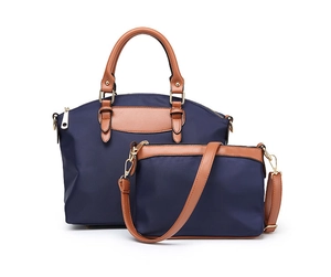 Close-up of navy nylon tote and crossbody bag set with brown leather handles and gold zippers