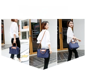 Three-way outdoor view of navy nylon handbag with brown leather handles and strap