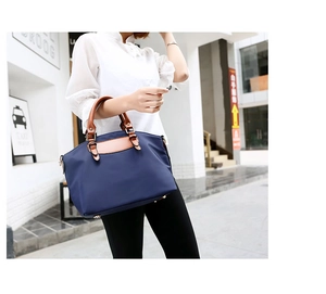 Deep blue nylon tote bag shown in a street style carry pose with leather handles