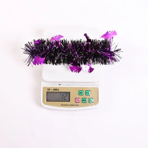 Detail shot of purple and black Halloween tinsel garland with bat sequins on a digital scale