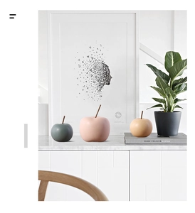 Detalle de manzanas decorativas de cerámica Morandi sobre un mueble blanco en salón moderno