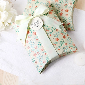 Floral pillow gift box with green ribbon and handmade tag on white linen background