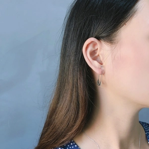 Close-up of a 925 sterling silver safety pin earring worn by a model in a side view