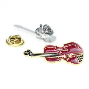 Detailed view of a vintage red and gold violin enamel pin with a silver butterfly clasp