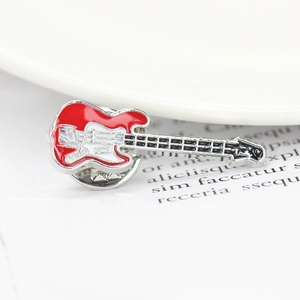 Macro shot of guitar brooch featuring red and white enamel on polished silver metal base