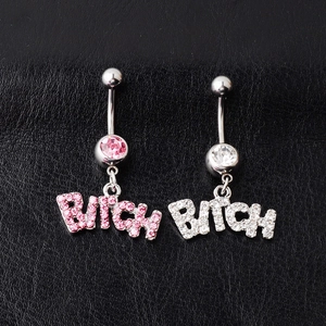Macro shot of silver belly rings with pink and clear crystals spelling out BITCH