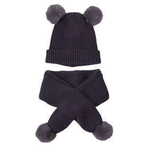 Close-up of knit winter set for kids featuring double faux fur pom-poms on hat and scarf