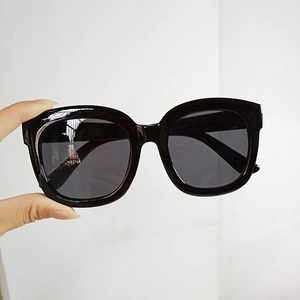 Detail shot of black square frame sunglasses with dark grey lenses and classic design
