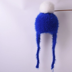 Detail of navy blue winter knit hat with large white faux fur pompom and long earflaps