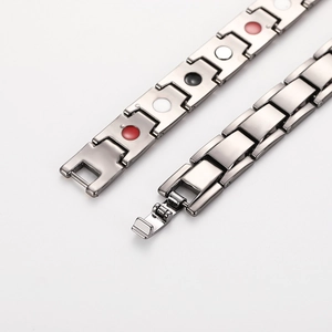 Detailed close-up of silver steel magnetic therapy bracelet with red, white and black elements