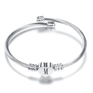 Macro shot of silver twisted cable cuff bracelet with an engraved heart initial M pendant