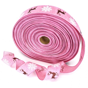 Detailed texture of pink burlap Christmas ribbon featuring brown reindeer and white snowflakes