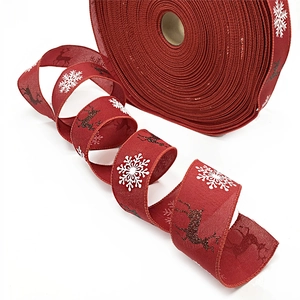 Close-up of red Christmas burlap ribbon with white snowflakes and golden reindeer patterns