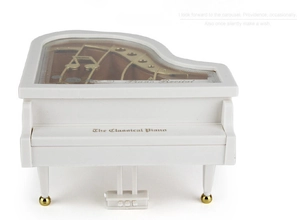 Close-up of white creative piano music box with golden movement and musical note detail