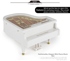 Detail view of white mini piano music box with transparent lid and gold movement