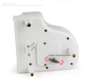 Detail view of the mechanical wind-up key and gold-rimmed legs of the piano music box