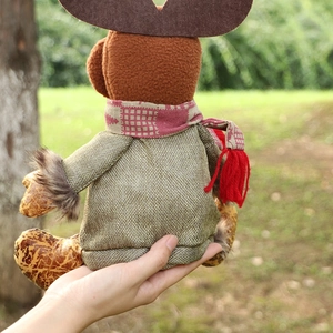 Plush Christmas reindeer doll with green sweater and red plaid scarf held in hand
