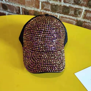 Detail of a black baseball cap with rose gold rhinestones on a yellow table