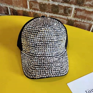Macro shot of black baseball cap fully covered in sparkling silver rhinestones on yellow background
