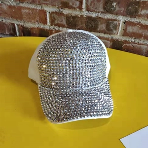 Close-up of a white baseball cap featuring sparkling silver rhinestones on the brim