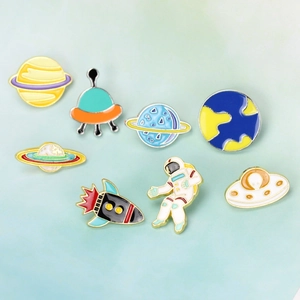 Flat lay of colorful enamel space brooches featuring astronauts, planets and rockets