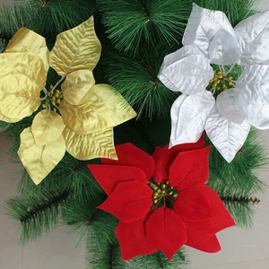 Detail of red, gold and silver velvet poinsettia flowers on decorative pine needles