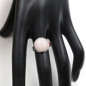 Detail of a round rose quartz stone set on a minimalist silver adjustable ring band
