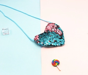 Detail of heart-shaped sequin crossbody bag with reversible pink and blue scales
