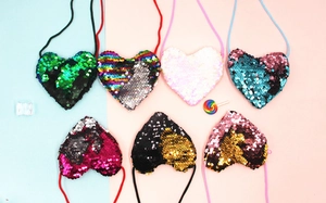 Flat lay of colorful heart-shaped sequin crossbody bags with lanyards for children