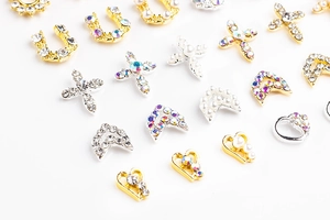 Detail of silver and gold alloy nail charms with rhinestones, pearls, and heart shapes