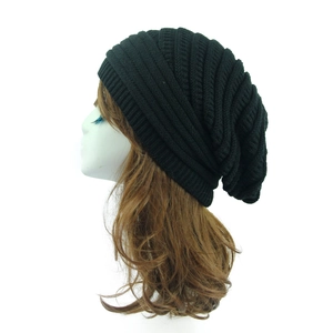 Detail showing the chunky knit texture and slouchy design of the black beanie on a model