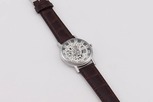 Detailed macro view of skeleton dial men's quartz watch with brown leather strap