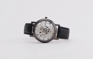 Detail of silver hollow gear dial with Roman numerals and black embossed leather strap