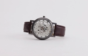 Detail of the hollow mechanical dial with Roman numerals and brown leather strap