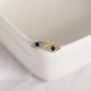 Macro detail of gold and silver S925 sterling silver evil eye stud earrings with blue zircon