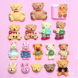 Collection of 16 DIY resin cartoon bear and rabbit charms on pink wood grain background