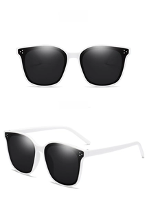 Detail of white square sunglasses with grey lenses and three decorative metal dots