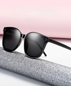Detail of black oversized square sunglasses featuring silver triple-dot accents on corners