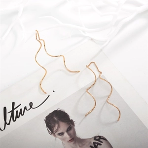 Detailed view of elegant rose gold S-shaped wave tassel threader earrings on white coral