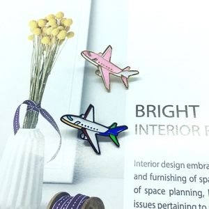Detailed close-up of pink glitter and colorful enamel airplane lapel pins on a magazine