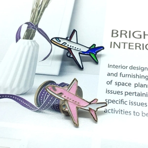 Detail of pink glitter and colorful enamel airplane lapel pins on a magazine background