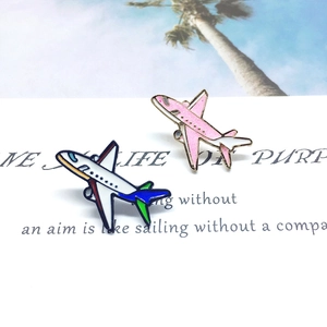 Detail of pink and blue airplane enamel pins displayed on a white decorative card