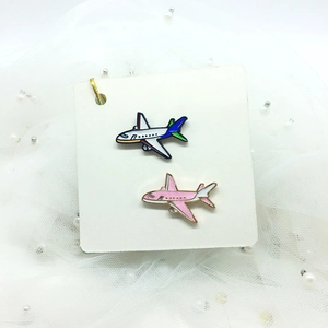 Detail of pink and blue airplane enamel pins on cardstock with pearl mesh background